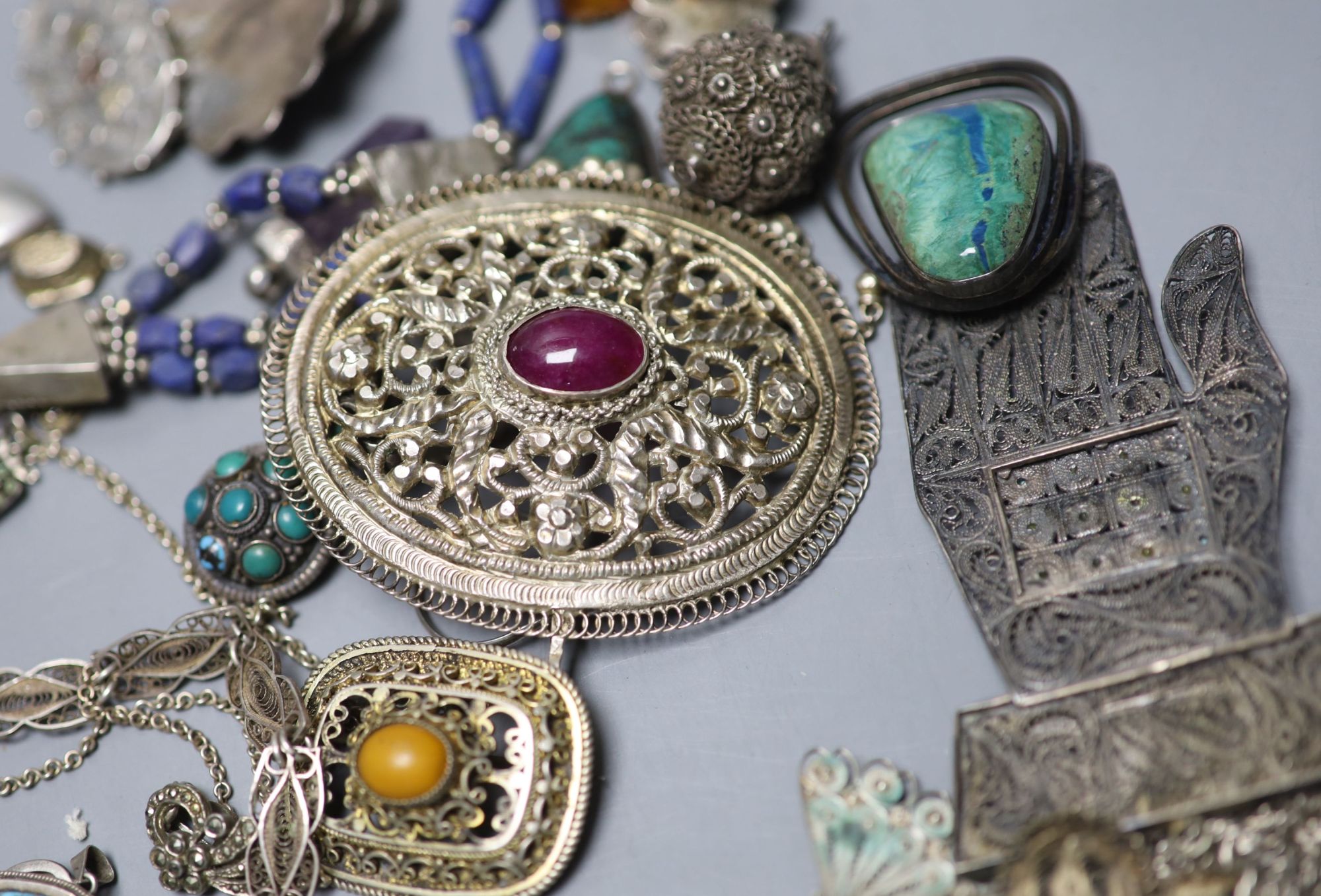 A mixed group of assorted white metal and costume jewellery including locket, brooches and filligree items.